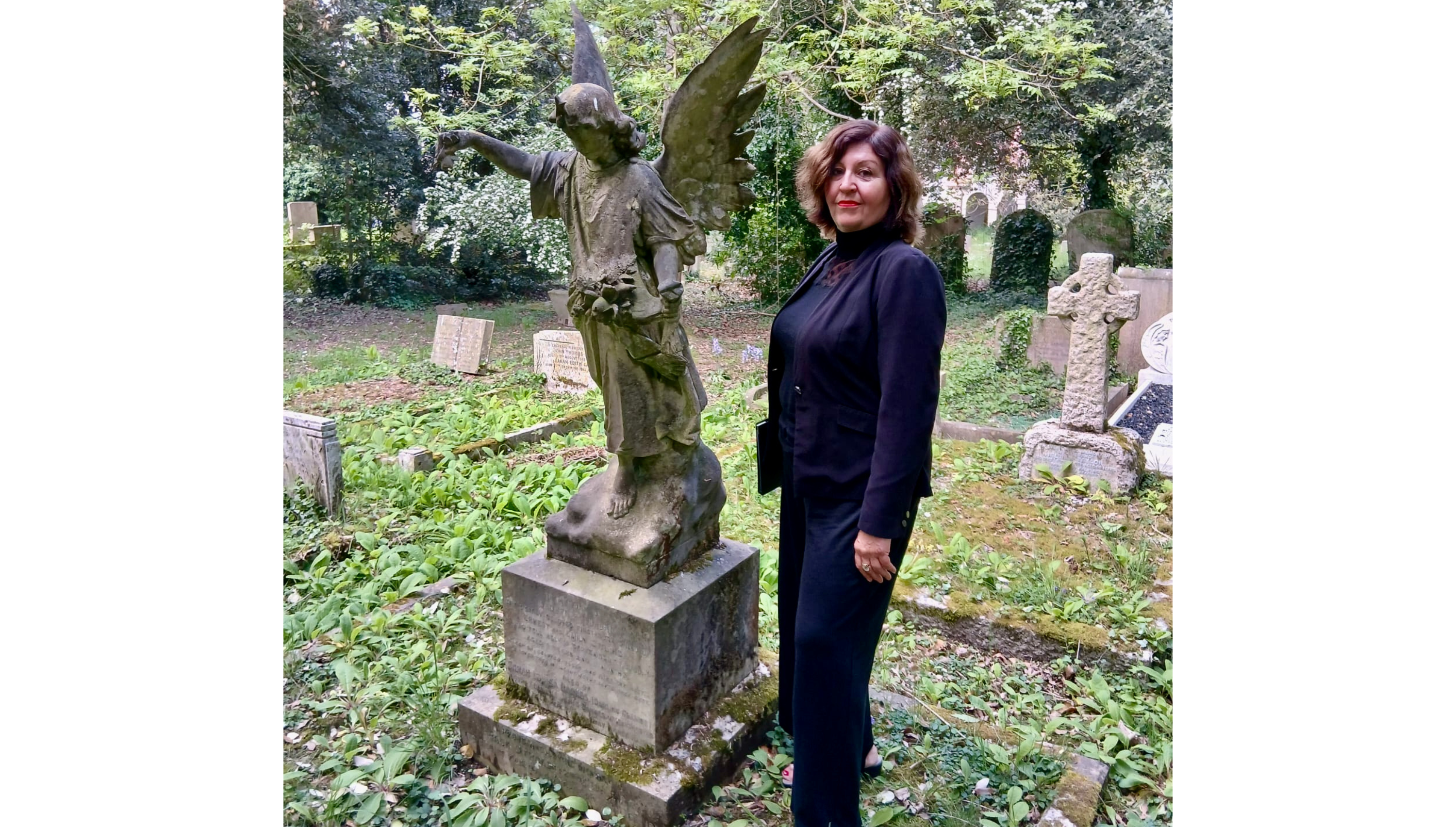 Journalist-turned-funeral celebrant Lynne Wallis in a black suit in a graveyard
