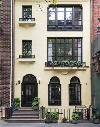 Image of a three-story, pale yellow town house with black trimmed windows that are detailed with muntins