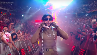 Bad Bunny walking to the ring with a chain around his neck and sunglasses on.