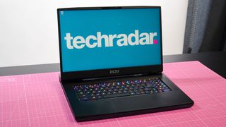 MSI GT77 Titan pinkillä pöytäliinalla TechRadar-logoa näyttämässä