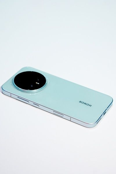 The Honor Magic 8 Pro in a light greenish-blue colorway, showing its rounded, centered camera array during the company's appearance at the Snapdragon Summit 2025 event.
