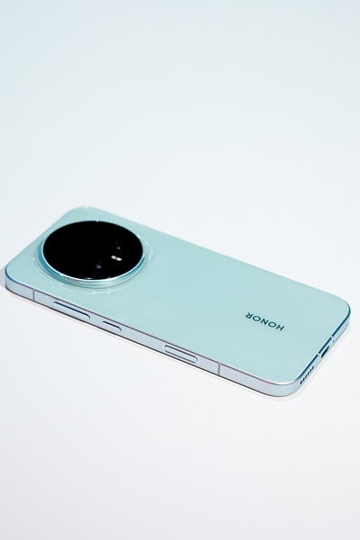 The Honor Magic 8 Pro in a light greenish-blue colorway, showing its rounded, centered camera array during the company's appearance at the Snapdragon Summit 2025 event.