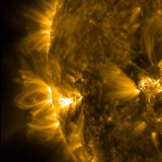 close-up view of curving yellow loops and bright spots on the sun's surface.