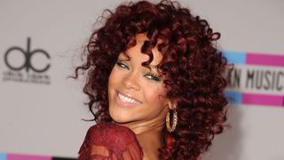 Rihanna pictured with burgundy red, curly hair whilst attending the 2010 American Music Awards held at Nokia Theatre L.A. Live on November 21, 2010 in Los Angeles, California