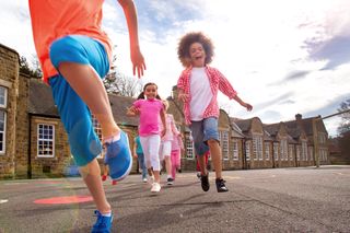 Kids running across a playground away from school