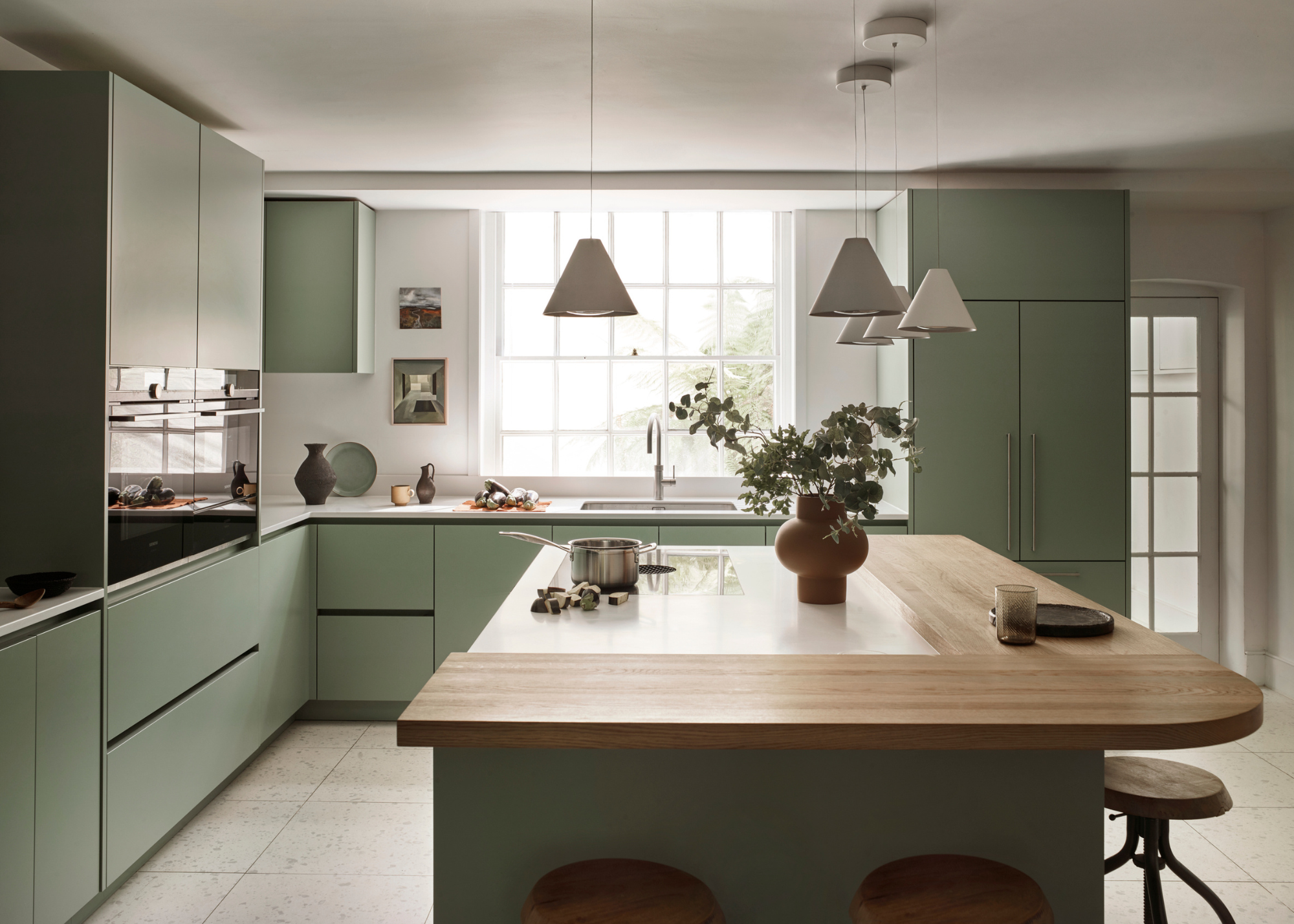 a sage green kitchen with wooden kitchen island and lots of natural light