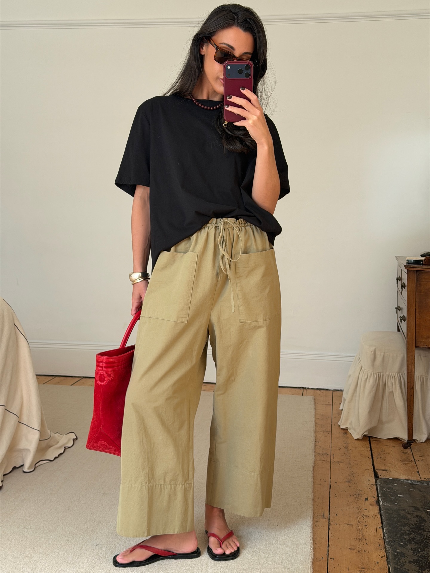 emswells wears a tee, linen trousers and a red bag with matching flip flops as a styling hack for summer 2026