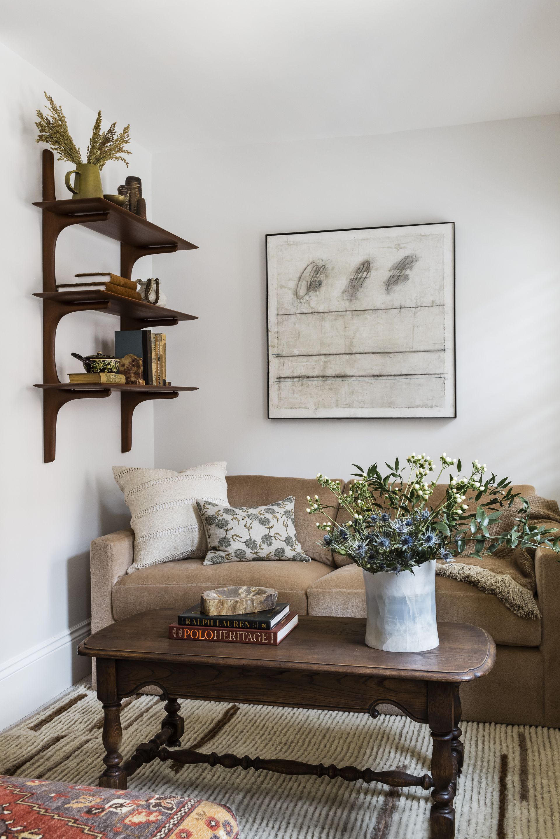 living room with sofa, open shelves with object and coffee table with books and plant