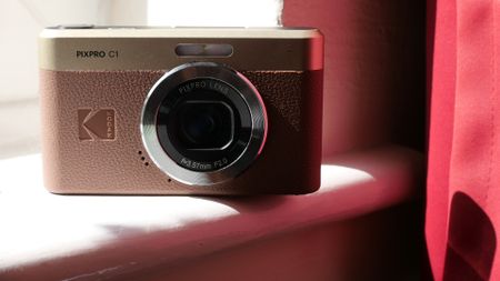 Kodak Pixpro C1 camera placed on a windowsill, showcasing its stylish design and lens under natural light.
