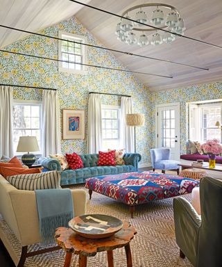 colorful living room with floral wallpaper, purple windowseat, blue sofa, patterned cushions and ikat footstool