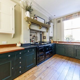 kitchen with white wall dark green cabinets and wooden flooring
