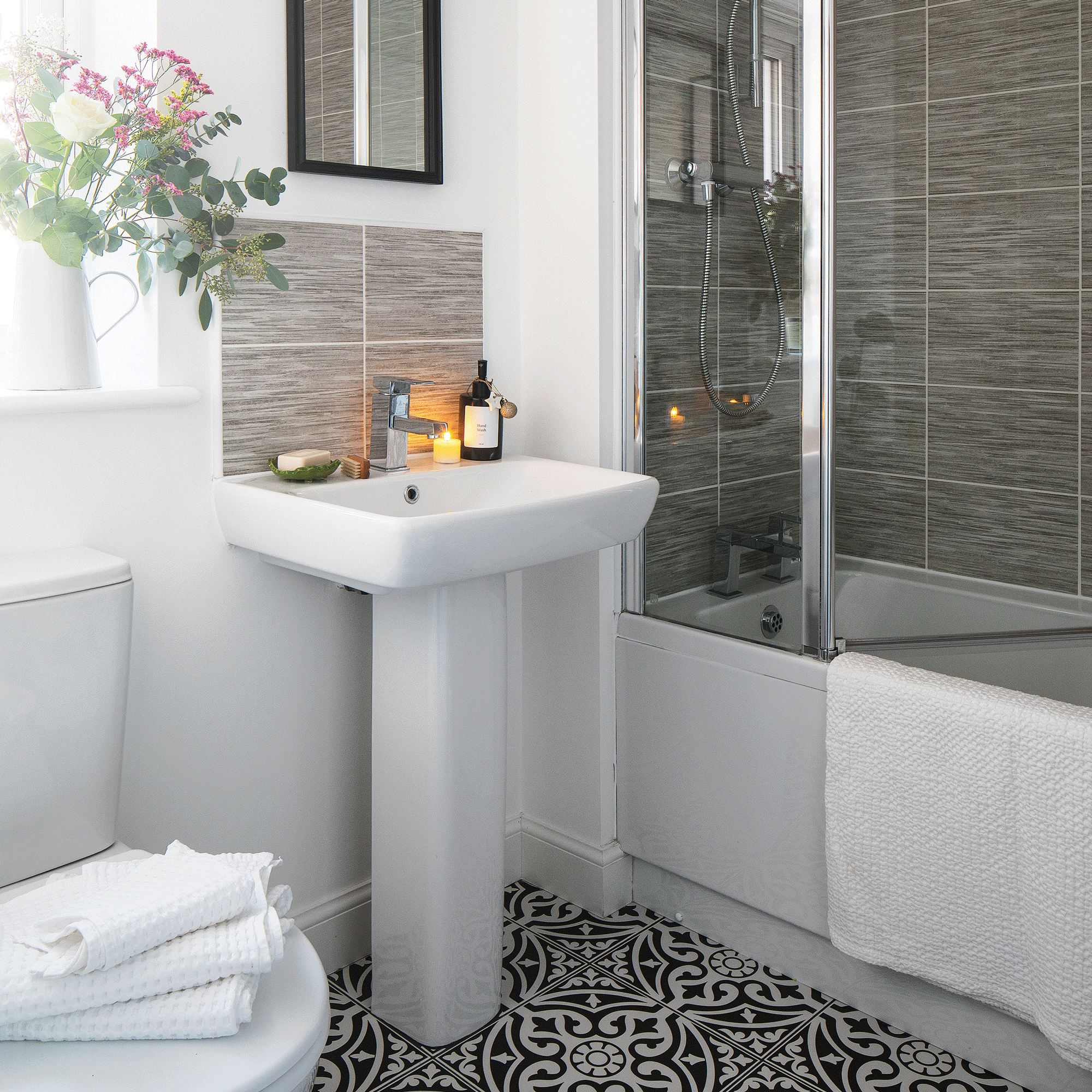 a neutral bedroom with shower bath and monochrome patterned floor tiles