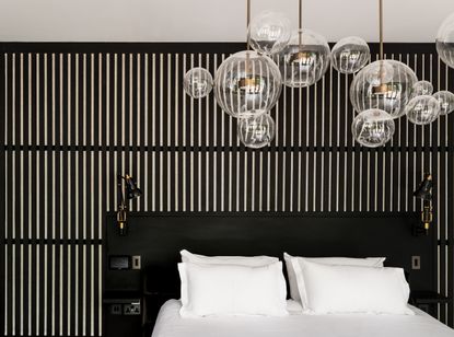A bedroom with a featured wall in wooden slats, painted black