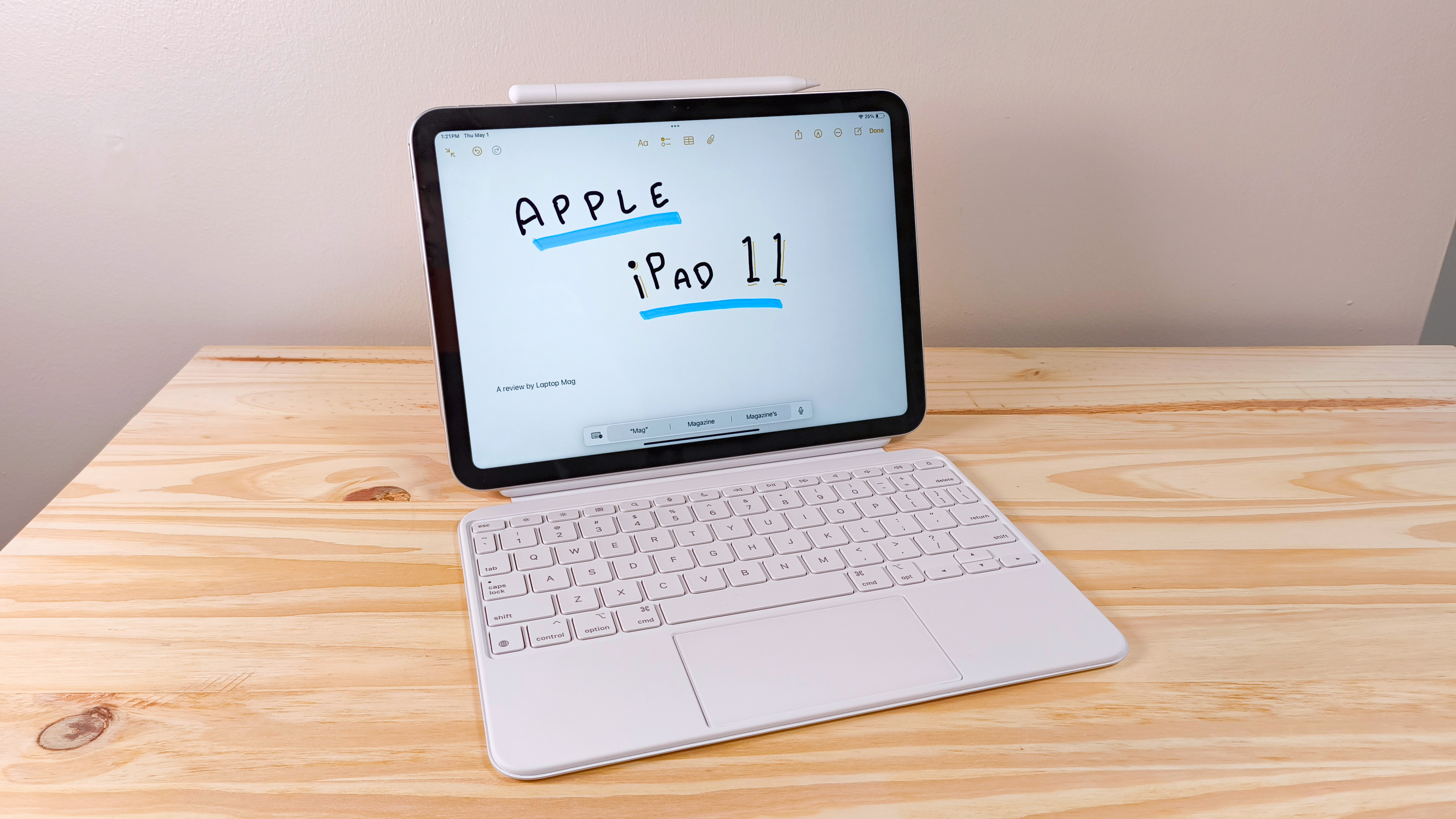 The iPad 11 propped up on a wood table connected to the Magic Keyboard Folio and Apple Pencil USB-C