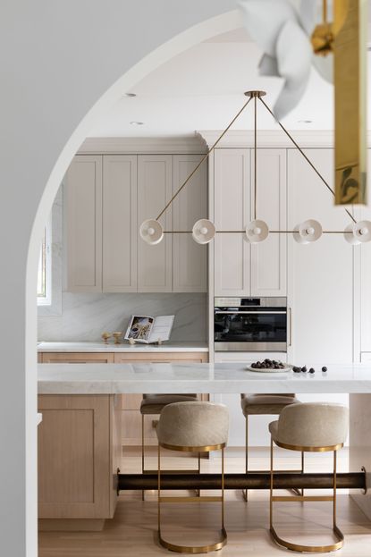 An example of how to make a small kitchen look bigger showing a kitchen with cream units and a glamorous light fitting