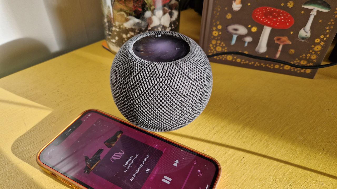 An Apple HomePod Mini on a table with an iPhone