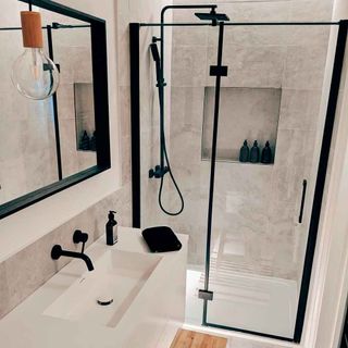 bathroom with shower and mirror on wall with glass partition with black frame bulb and faucet