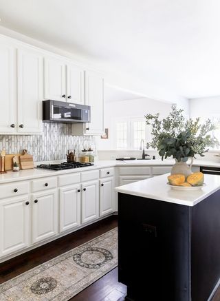 A kitchen with white cabinetry and a black island