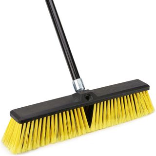 A yellow and black outdoor cleaning brush