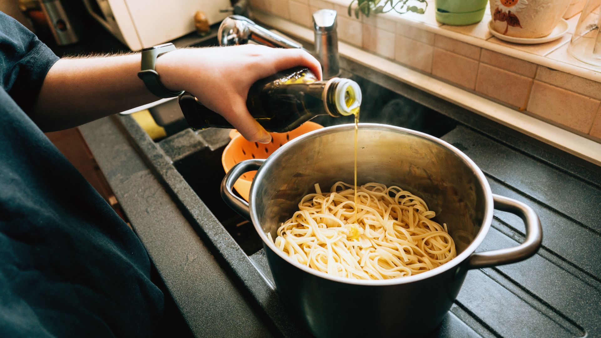 Woman adding oil to pasta