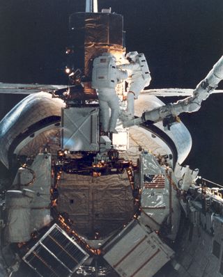 STS-41C astronauts George D. Nelson, right, and James D. van Hoften share a repair task at the captured Solar Maximum Mission Satellite in the aft end of the shuttle Challenger's cargo bay.