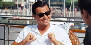 Leonardo DiCaprio points to himself with thumbs as he smiles in The Wolf of Wall Street.