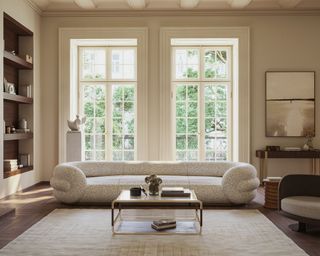 Large neutral living room with curvaceous cream sofa, two large windows, large cream carpet, metal coffee table