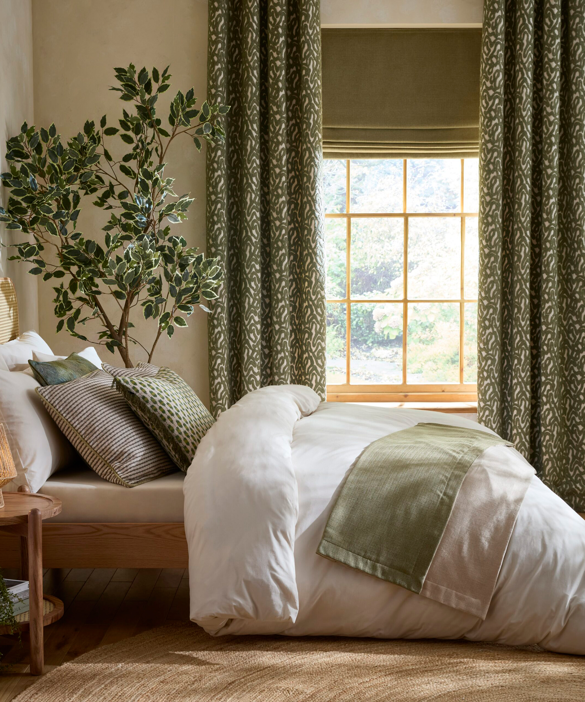 bedroom with long green patterned curtains and green velvet blind