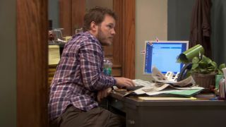 A screenshot of Chris Pratt looking at a computer in Parks and Rec.