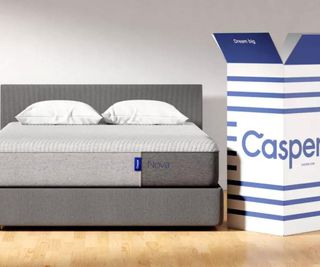 A Casper mattress on a bed beside a Casper delivery box.