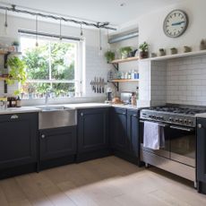 Navy kitchen cabinets with white brick tiles, range cooker,butler sink, industrial open shelving