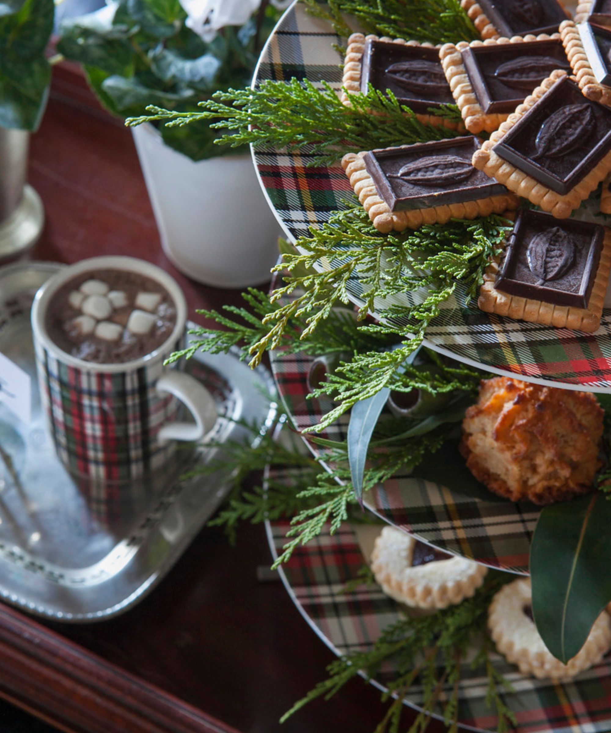 Three-tiered tartan cake stand filled with sweet treats and a mug of cocoa