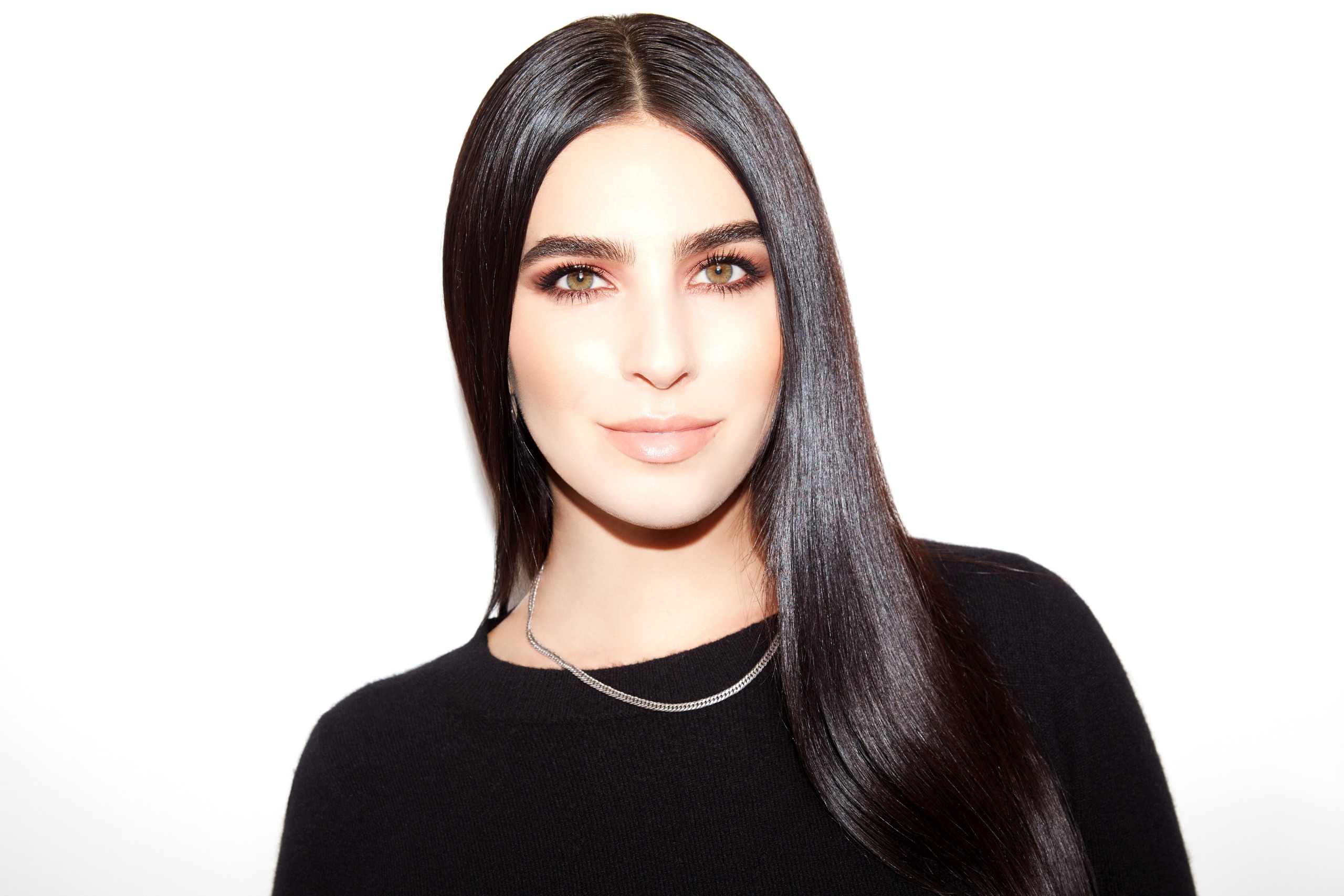 a white woman with long dark hair in a black top with a gold necklace