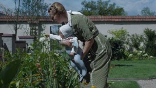 Sandra Hüller as Hedwig Höss with a baby in the garden in The Zone Of Interest