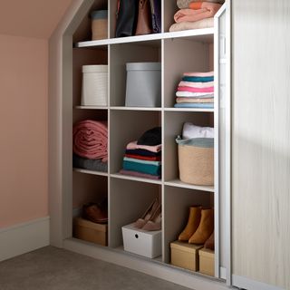 Sliding wardrobe door open showing cubicles with clothing and accessories