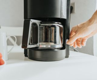 A drip coffee maker being switched on to make drip coffee