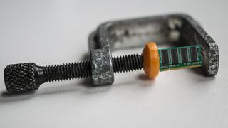 A manipulated photograph of a G-clamp holding a memory SO-DIMM.