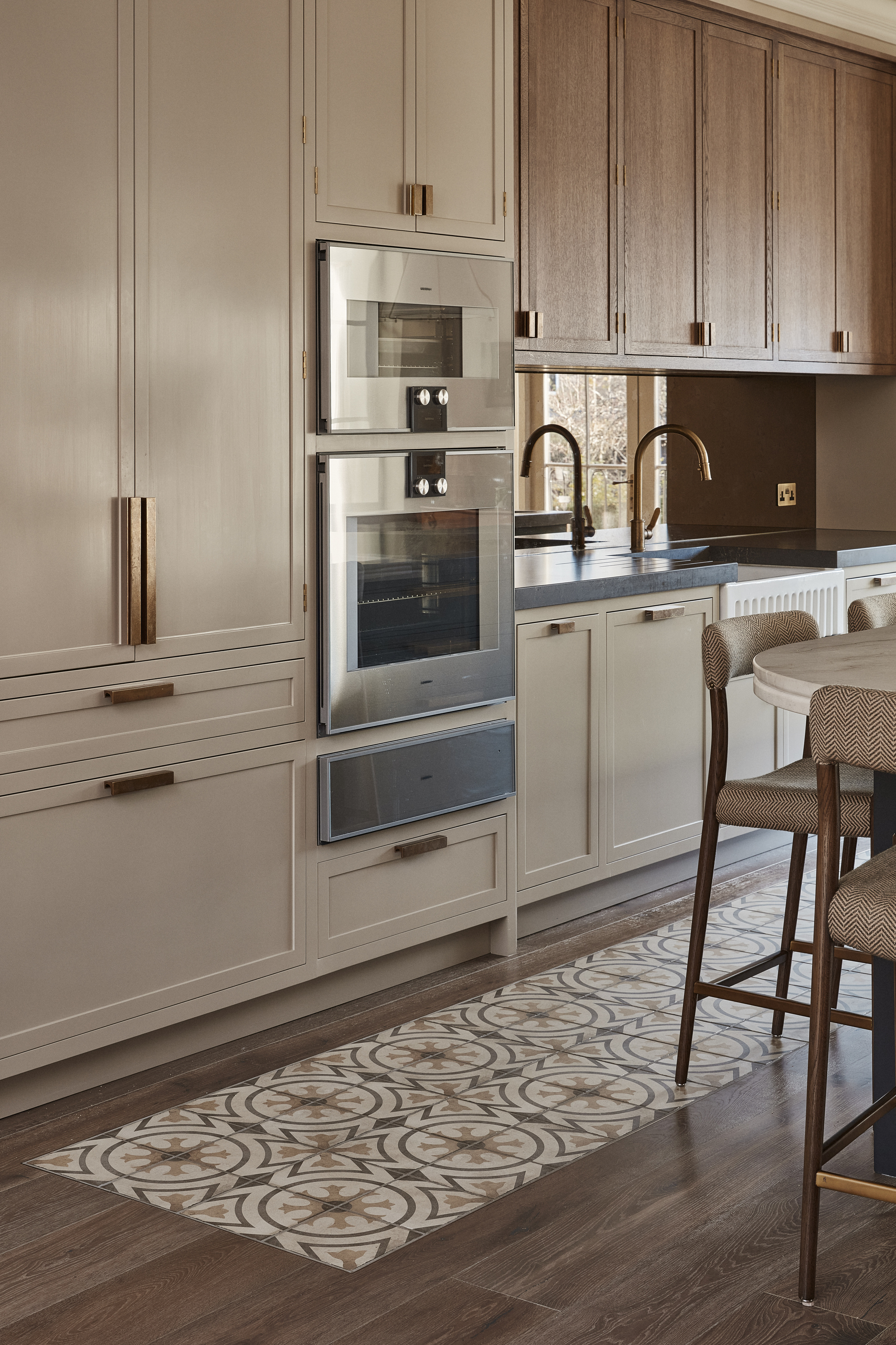 A modern kitchen with dakrk wooden floorboards with an integrated tile area running along the kitchen workspace