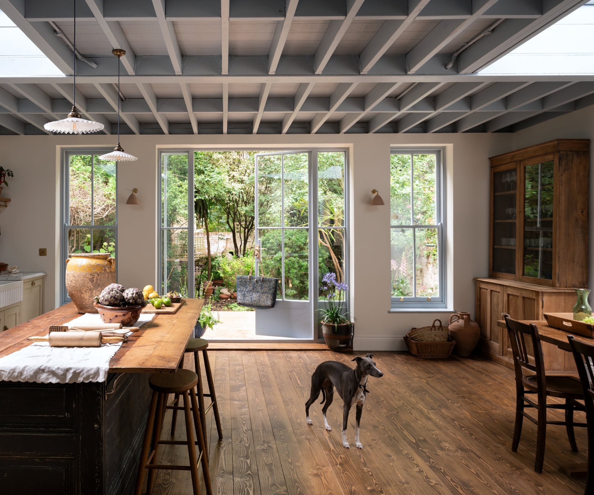 An open plan kitchen with cream cabinets, a vintage prep tables, and a freestanding wood hutch