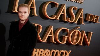 Tom Glynn-Carney in a black jacket stands in front of the Spanish logo for House of the Dragon at the season finale premiere in Madrid on October 24, 2022