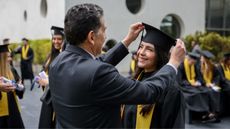 A proud father arranges the mortarboard of his college graduate daughter.