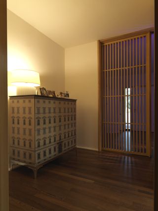 room with cream walls, wooden floors, patterned unit and wooden slat room divider