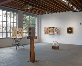 Display of sculptures by Tom Sachs in a white painted blick room with concrete floor and large paned windows