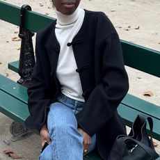 woman in black coat, turtleneck, and jeans