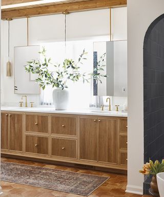 Bathroom with double vanity with mirrors above, white walls, tile floor and patterned bathroom rug