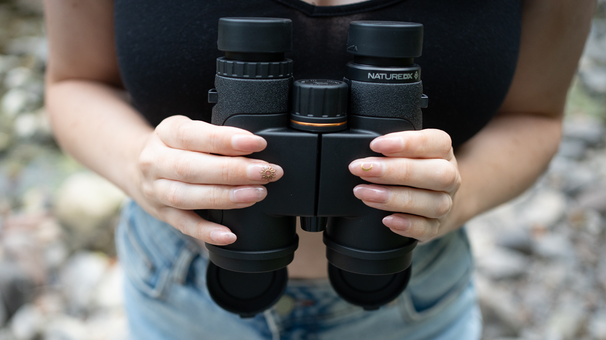 woman using the Celestron Nature DX 10x42 next to a river