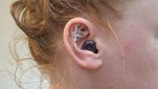 A black circular earbud in a close-up of an ear