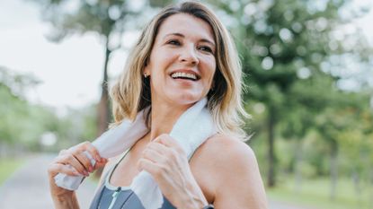 Woman in her 50s laughing, holding a towel around her shoulders after doing strength training exercises for women over 50