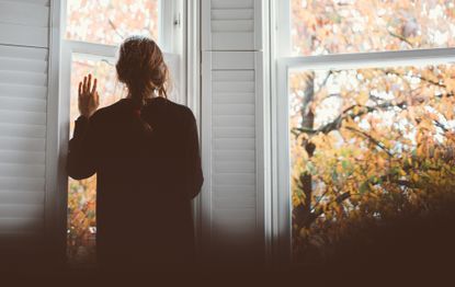 Woman looking out of the windown and feeling lonely - a sign of depression