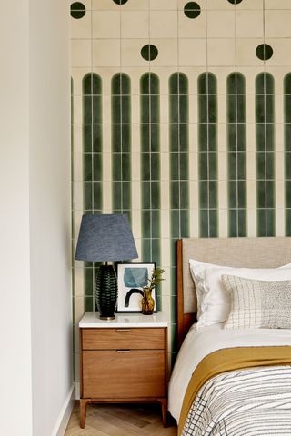 bedroom with green patterned tiles behind bedhead